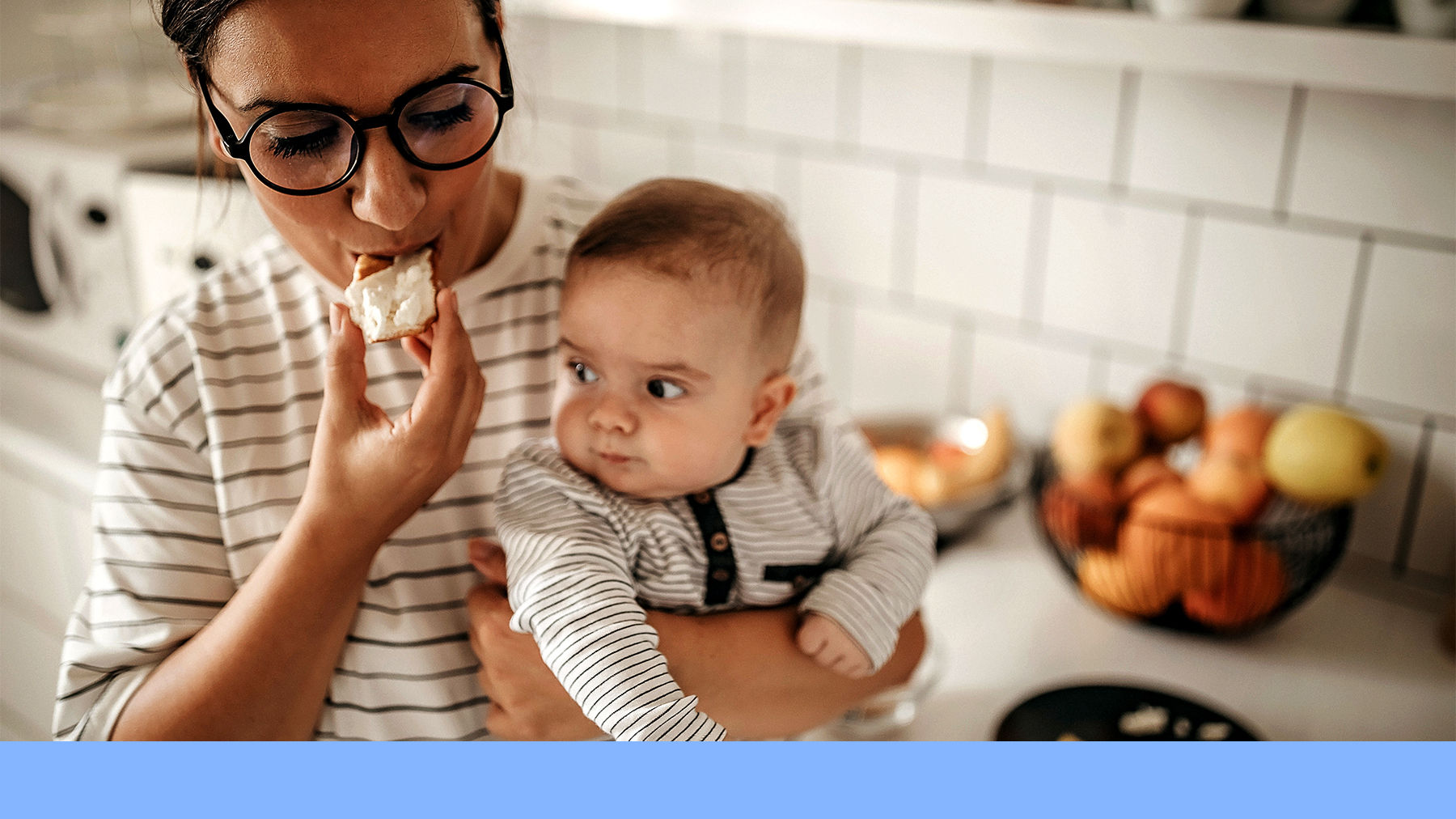 Mother eating a snack and holding a baby