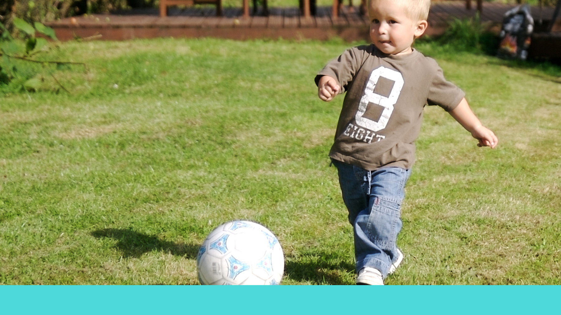 Toddler playing football in the garden